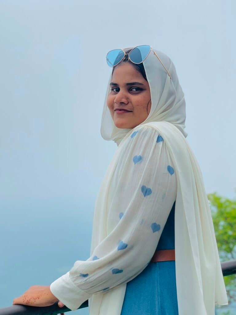 Fathima Rinsha MK, Freelance Digital Marketing Expert in Malappuram, posing outdoors in a white heart-print hijab and sunglasses against a clear blue sky.